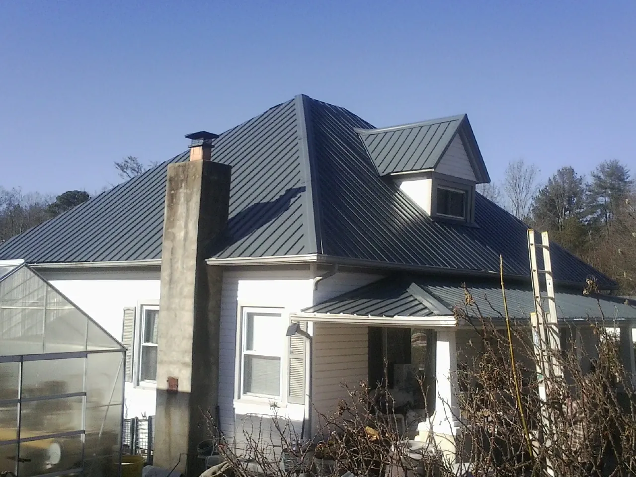 Dark blue standing seam metal roof on a white farmhouse with dormer — Slate & Tile Roof Repair by Roofing Brothers in Maria Stein