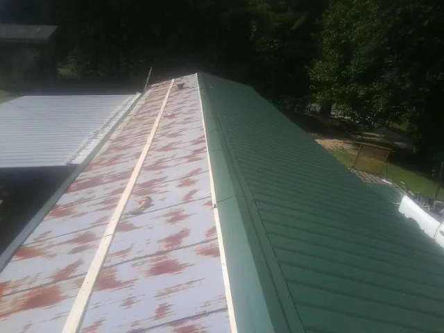 Old rusted panels beside newly installed green metal roofing — Wind Damage Roof Repair by Roofing Brothers in Maria Stein