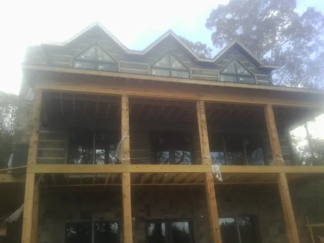 Dormers and porch framing on a large log home under construction — Roof Coating work by our crew in Maria Stein