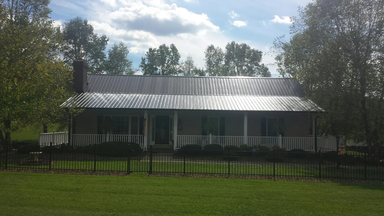 Gray metal roof on a brick ranch with a full width front porch — Gutter Guard Installation work by our crew in Maria Stein