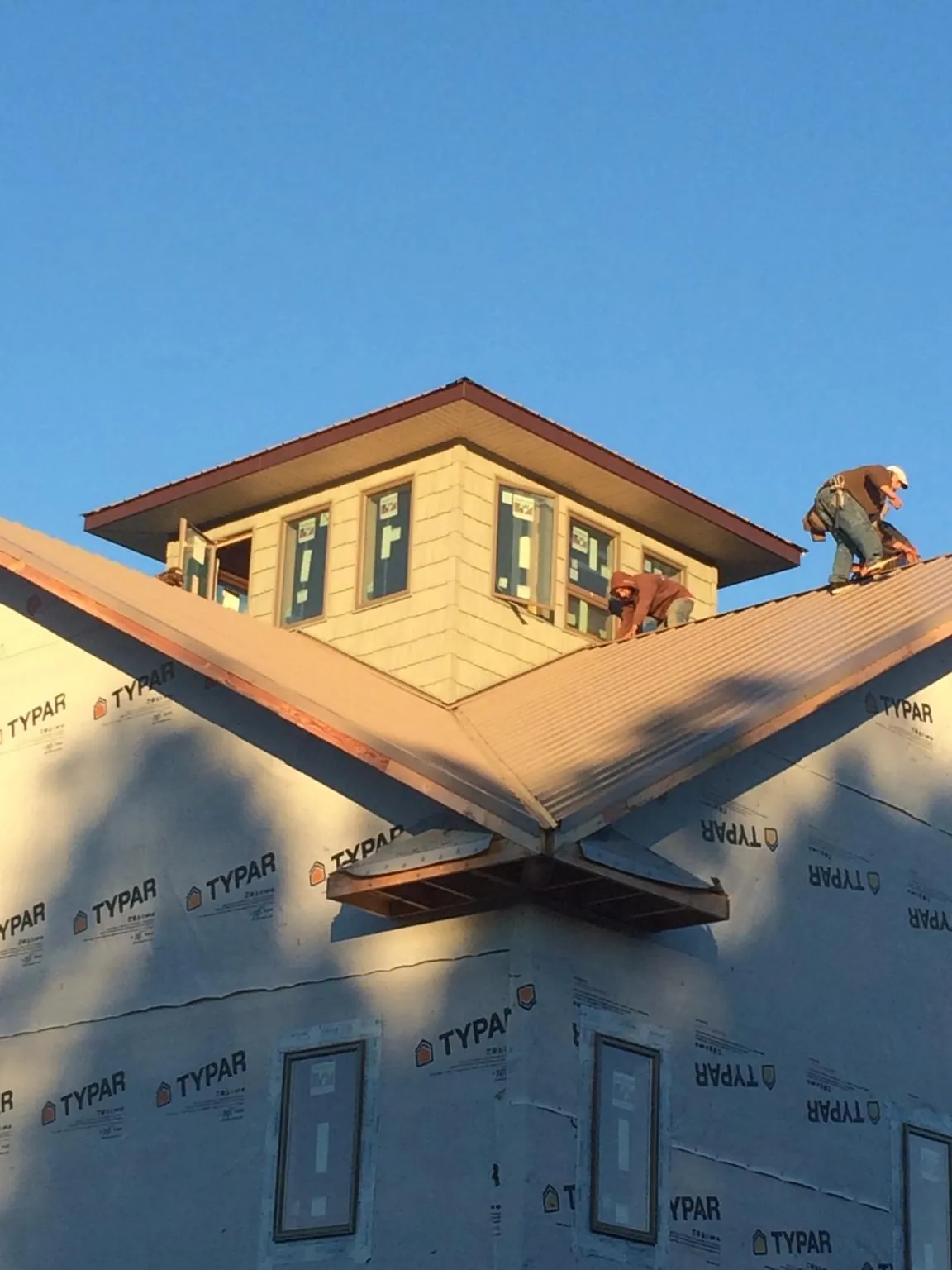 Roofers working around a rooftop cupola on a new metal roof at sunset — Roof Waterproofing in Maria Stein by Roofing Brothers